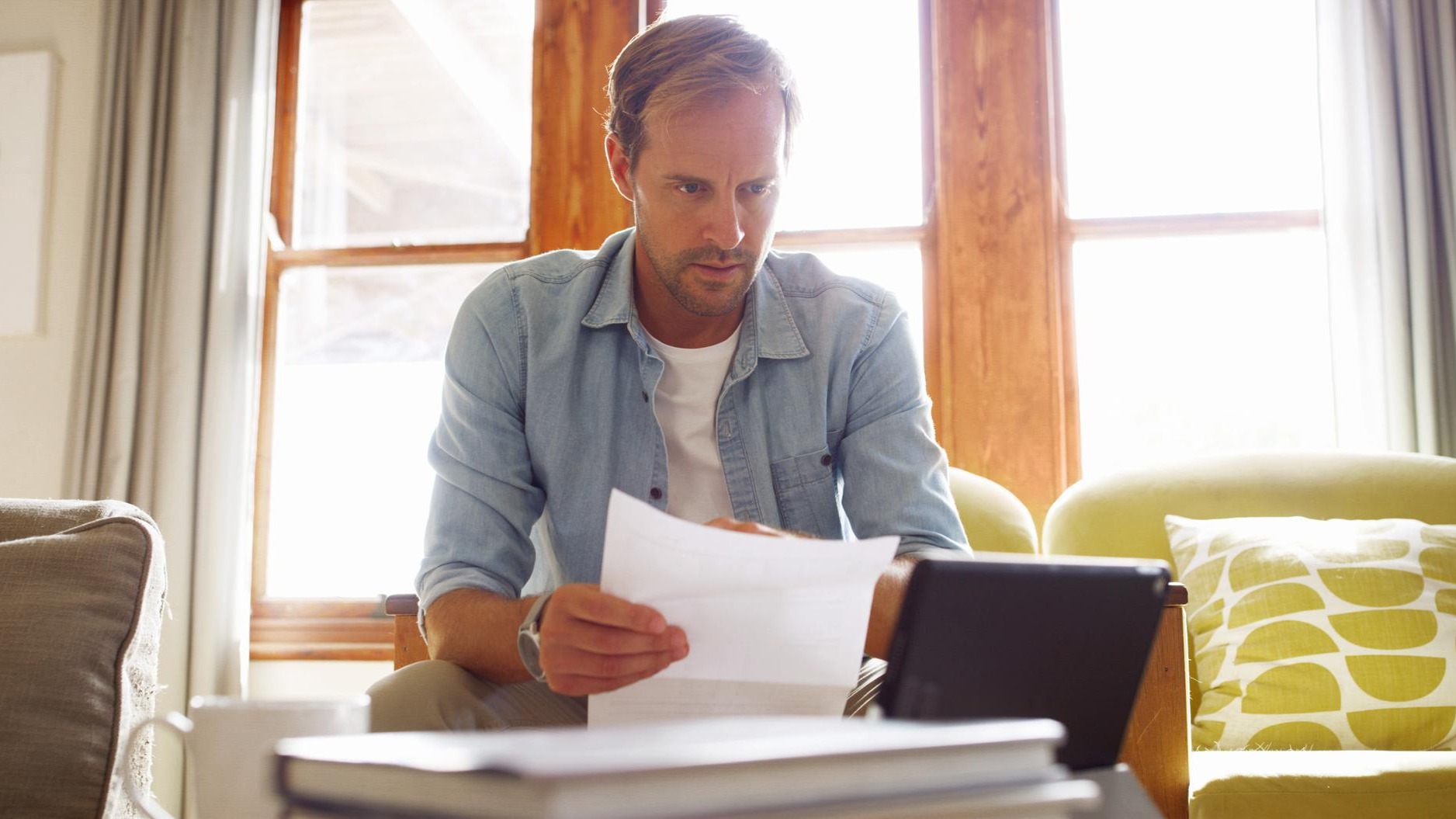 Documents tablet and man in living room planning for debt mortgage or tax payments in home Paperwork digital technology and male person with credit application savings or monthly budget in house