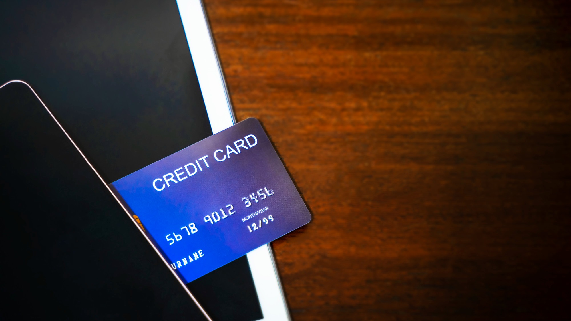 Credit card with mobile and tablet on wood table