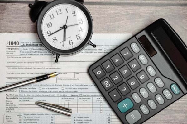 Top view tax form 1040 with pen calculator and black alarm clock tax time financial document