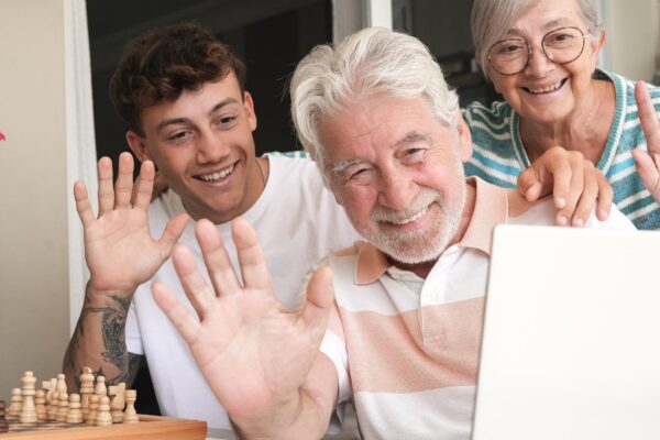 Happy multi generation family enjoying free time together sitting on terrace video call by laptop