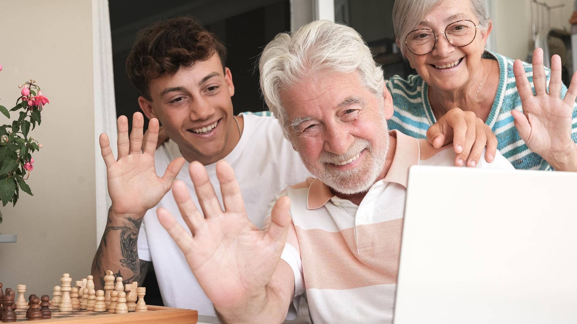 Happy multi generation family enjoying free time together sitting on terrace video call by laptop