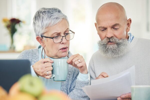 Laptop senior couple and finance documents in home for budget savings or taxes in house Computer retirement and man and woman with paperwork for financial planning insurance or bills with coffee