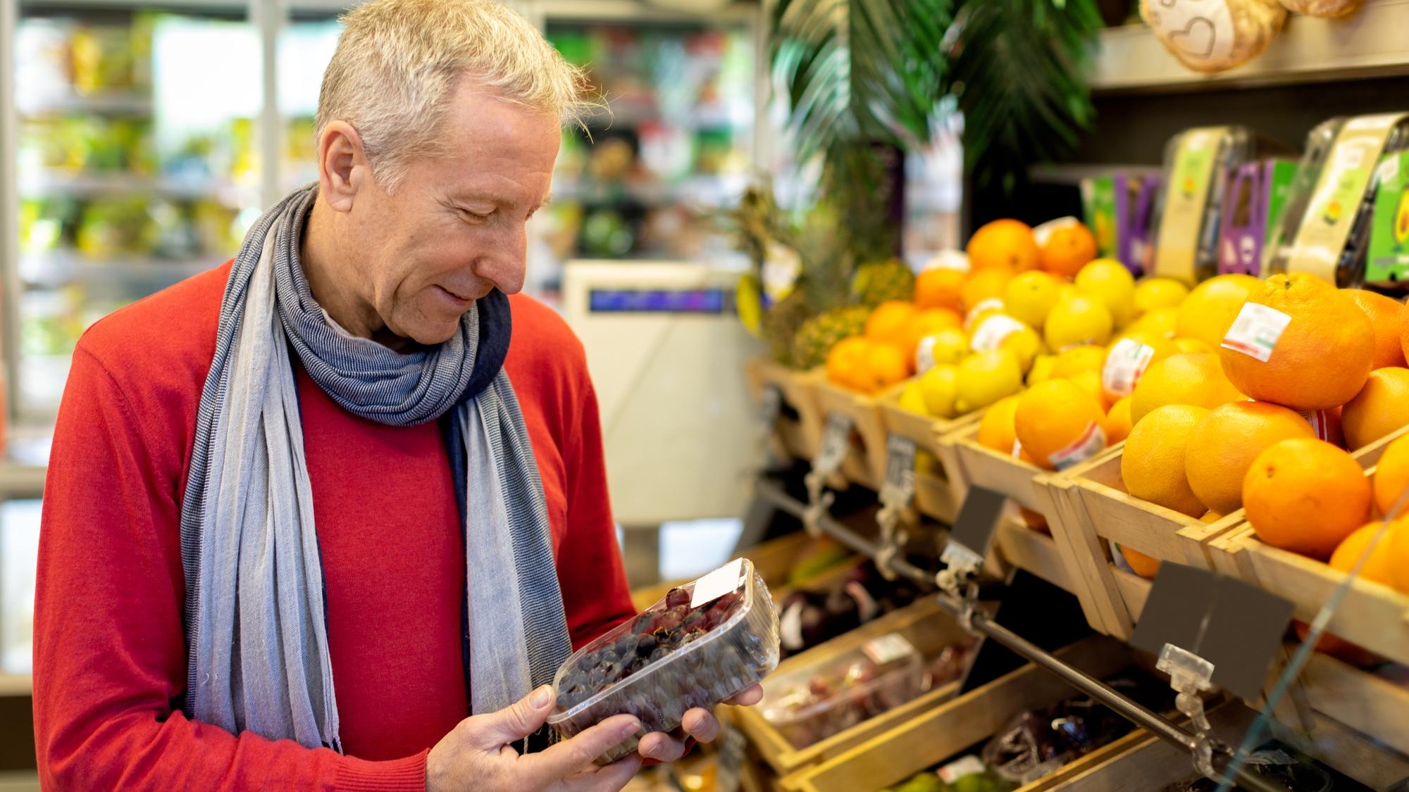 Goodlooking elderly man choosing fresh organic fruits at supermarket