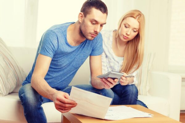 tax, finances, family, home and happiness concept - busy couple with papers and calculator at home