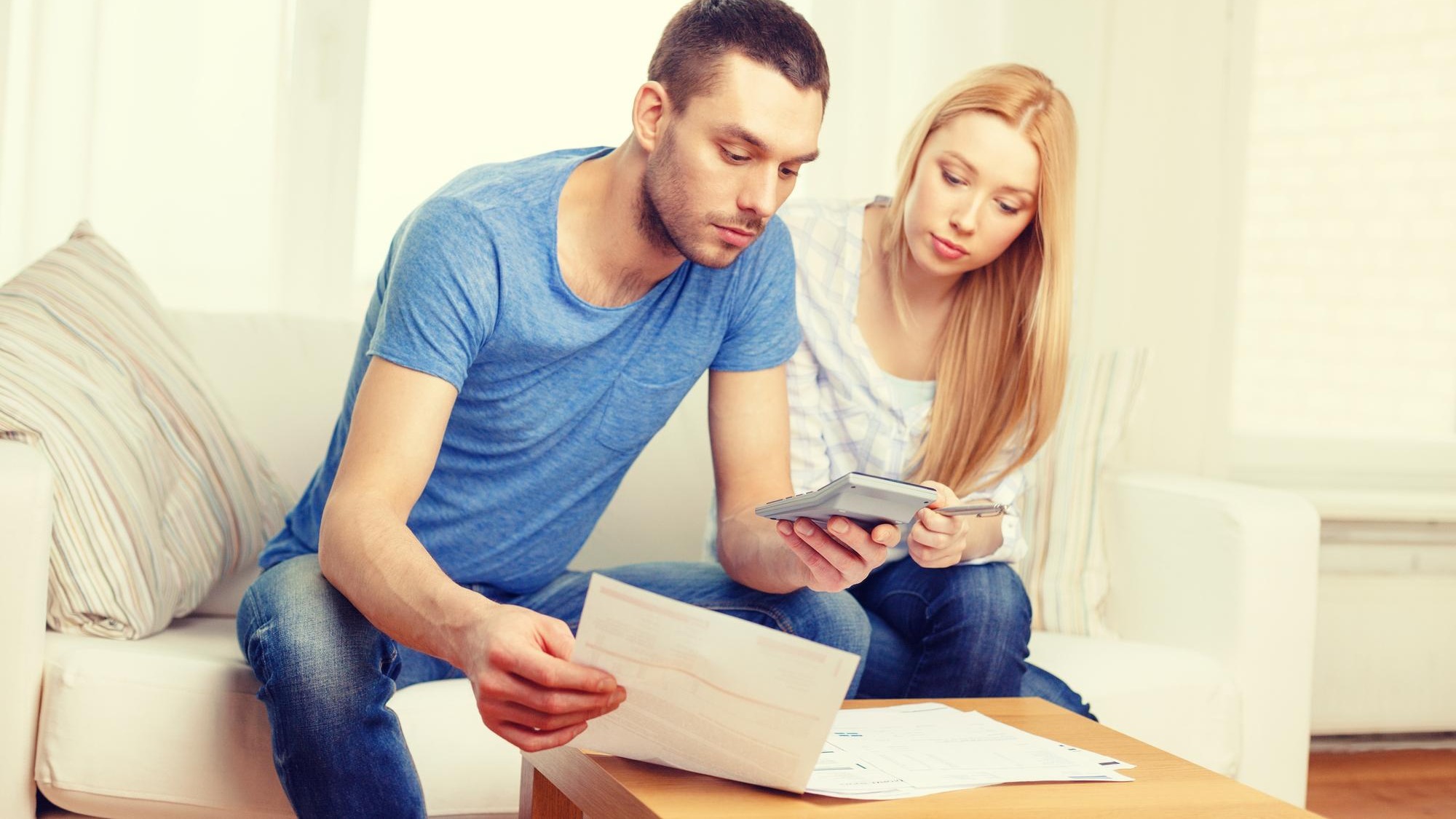 tax, finances, family, home and happiness concept - busy couple with papers and calculator at home