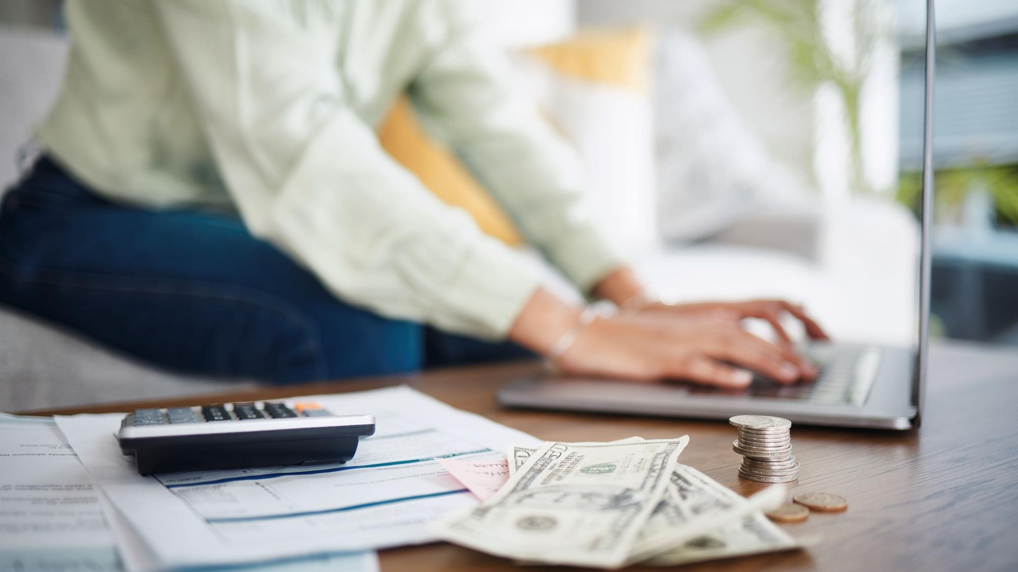 Laptop money and calculator with hands for home budget financial planning and salary rent cost or loan research Person typing on computer and sofa with cash and documents mortgage or bills