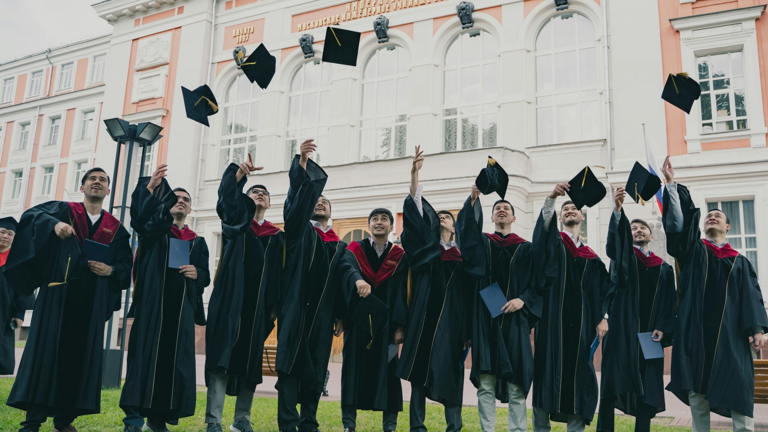 a group of people in graduation gowns holding their caps up