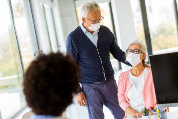 Senior couple with protective facial masks receive news from black female doctor