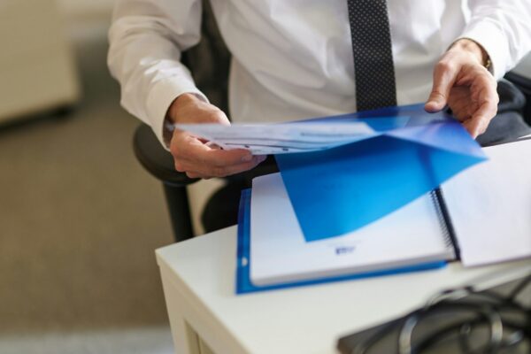 a man in a white shirt and tie holding a folder