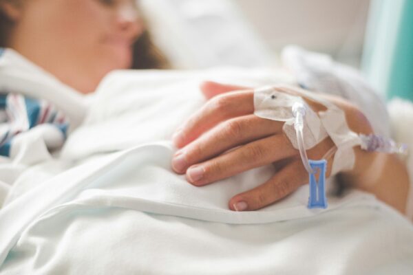 a woman laying in a hospital bed with an iv in her hand