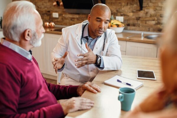 African American doctor communicating with mature couple during home visit