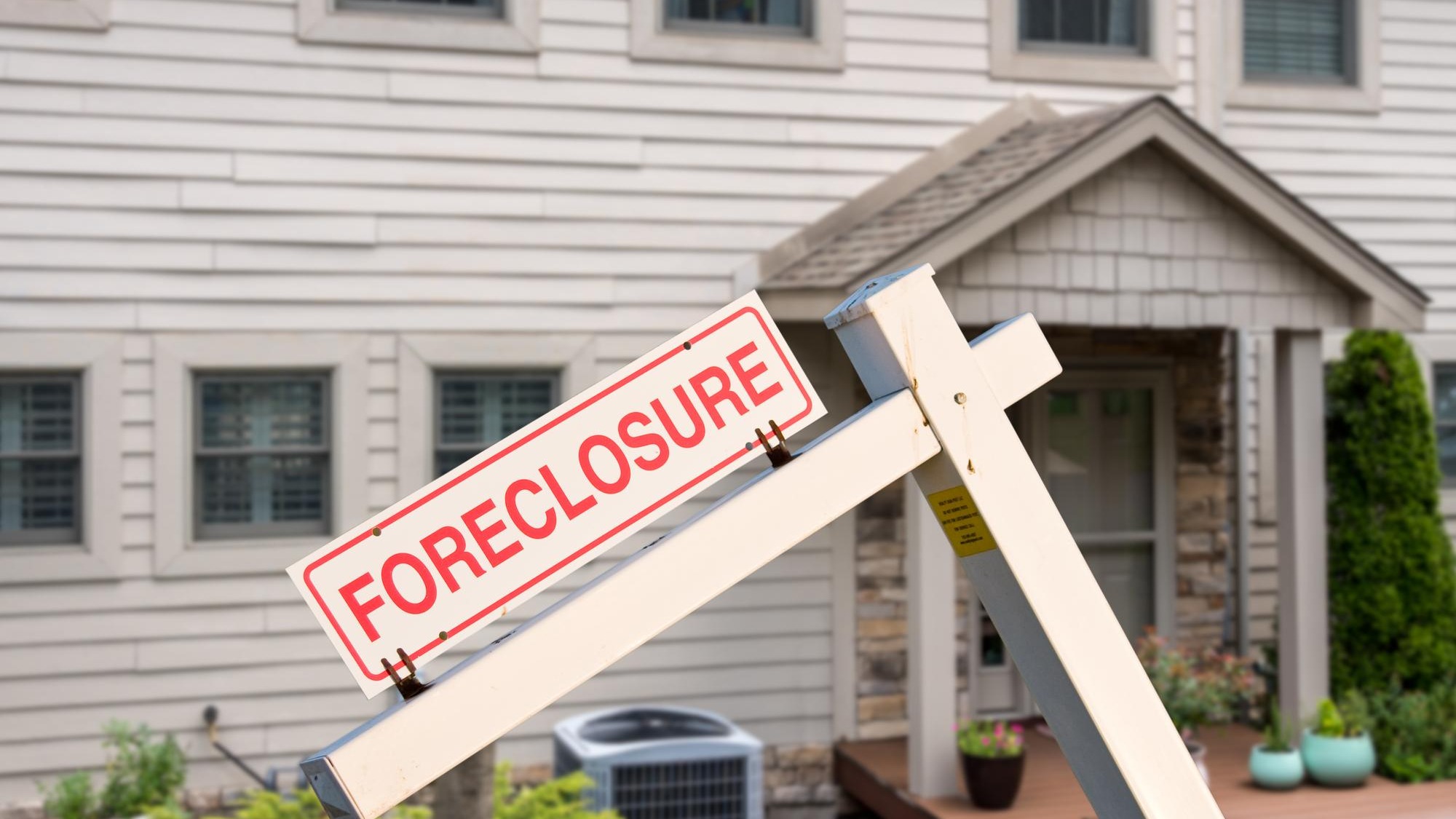 Mockup of a foreclosure sign in front of a modern townhome or townhouse to illustrate recession fears due to coronavirus