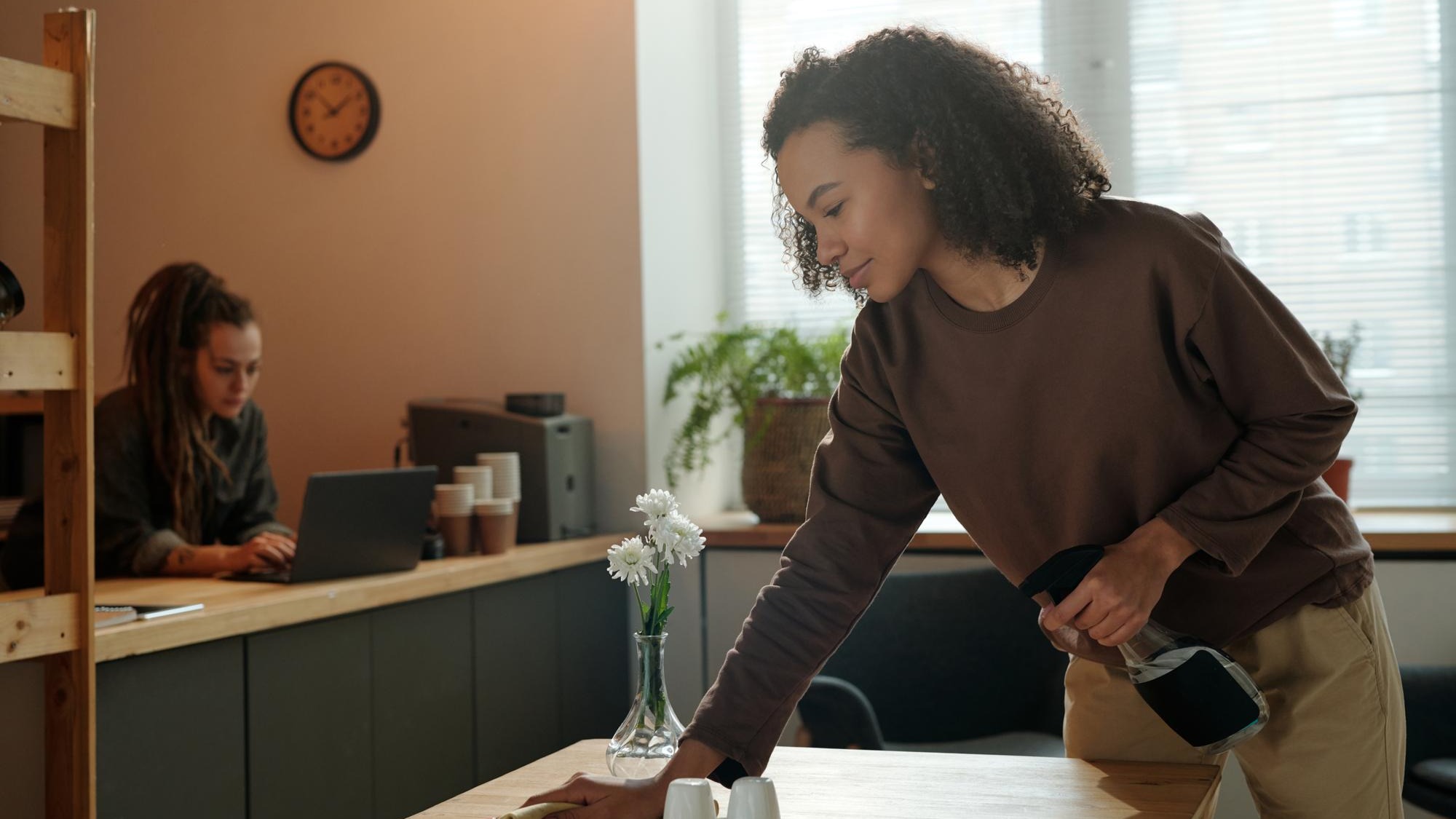 Cafe owner wiping table with duster