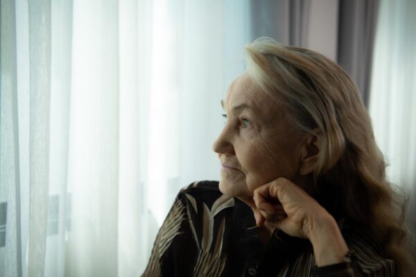 Lonely old woman Sit and look out the window where the morning sun shines in Miss my loved