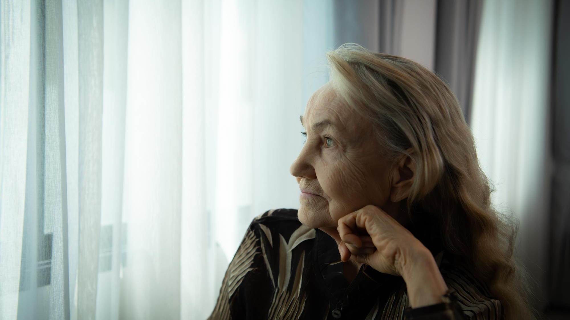 Lonely old woman Sit and look out the window where the morning sun shines in Miss my loved
