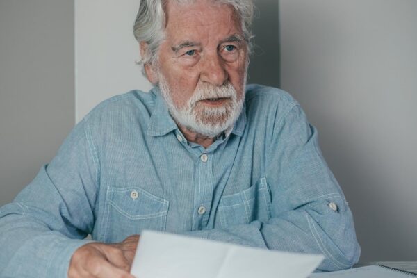 Senior bearded financial advisor man consulting documents sitting indoor at home