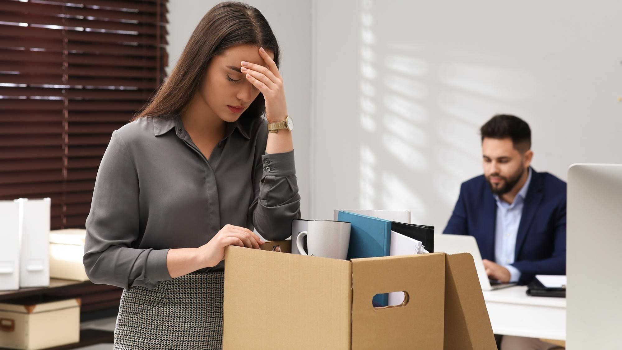 Dismissed woman packing personal stuff into box in office