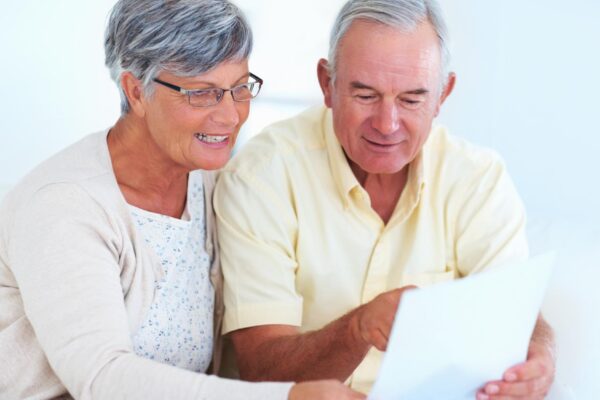 Home senior couple and budget with document for finance track expenses and discussion with bill Communication man and woman with paper for checking savings and review investment in retirement