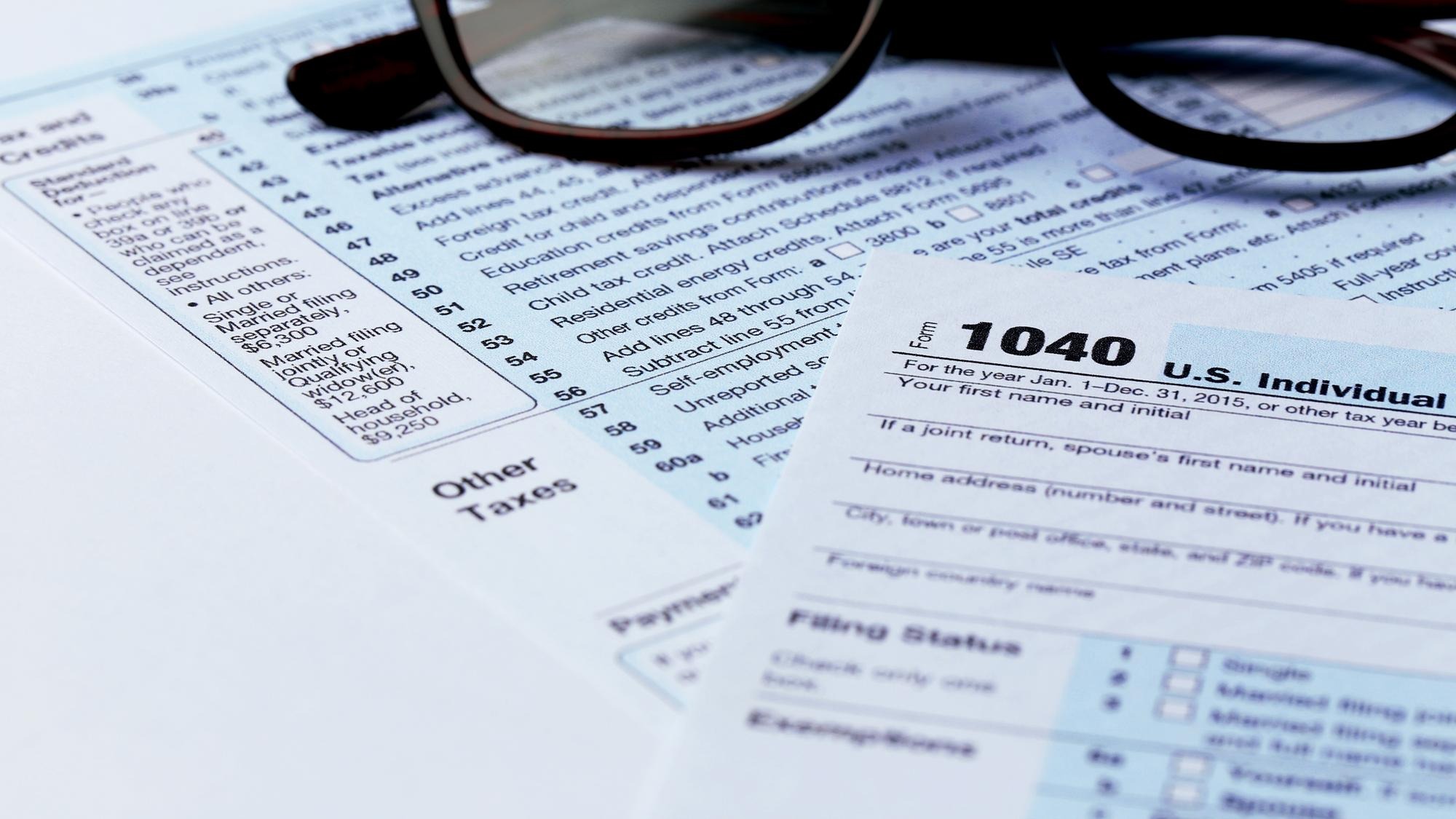 1040 Individual Income Tax Return Form with black rimmed glasses close up