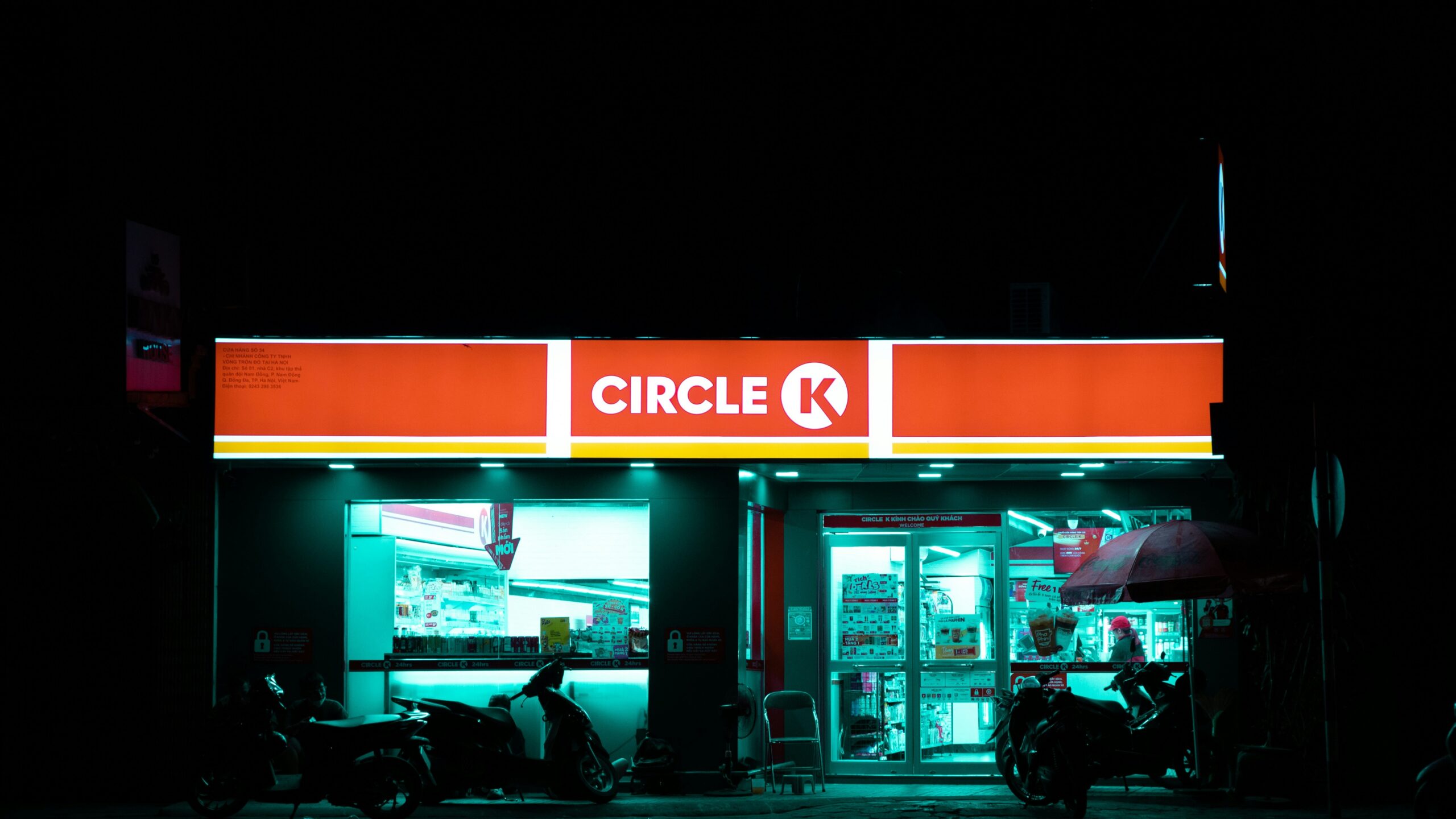 a store front at night with a motorcycle parked in front of it