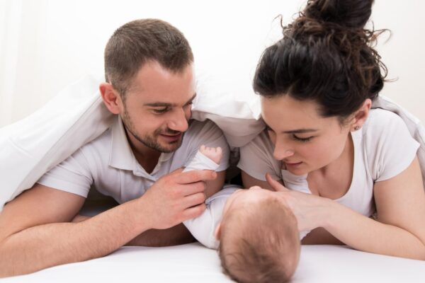 Family With Baby in Bed Under a Blanket