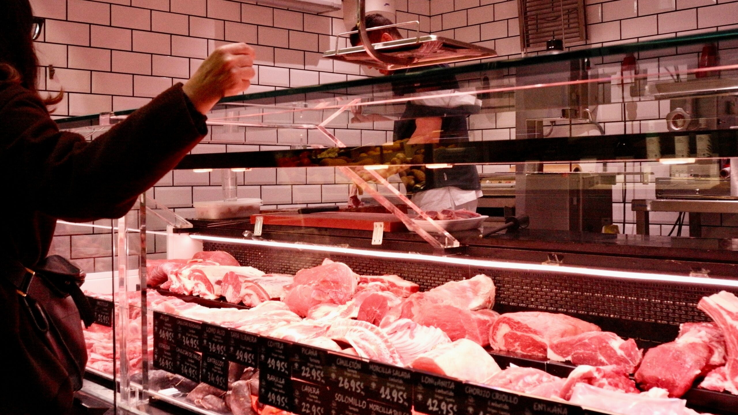 Customer selects raw meat from butcher display case