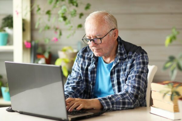 Elderly man working on computer while sitting at home