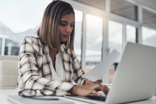 Business analyst laptop and woman typing documents in office workplace Paperwork analysis computer and female Indian person reading analytics for data graphs or charts for finance statistics