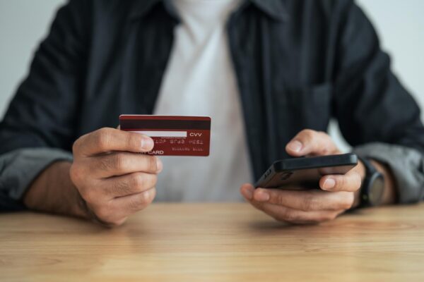 Man holding credit card and using mobile to shopping online asian man working at home Online shopping ecommerce internet banking spending money working from home concept