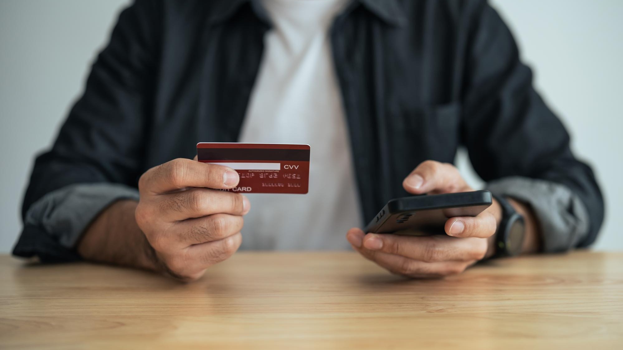 Man holding credit card and using mobile to shopping online asian man working at home Online shopping ecommerce internet banking spending money working from home concept