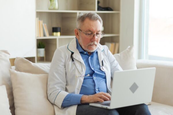 Senior man doctor working with laptop computer professional senior mature healthcare expert searchin