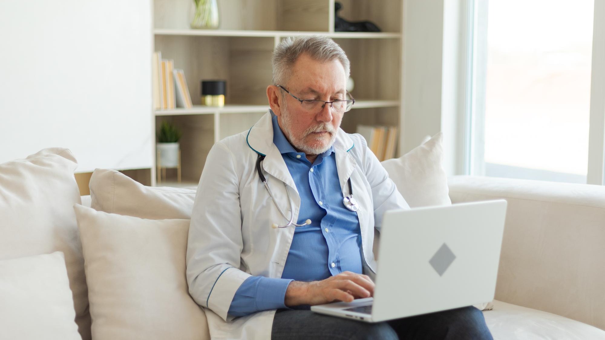 Senior man doctor working with laptop computer professional senior mature healthcare expert searchin
