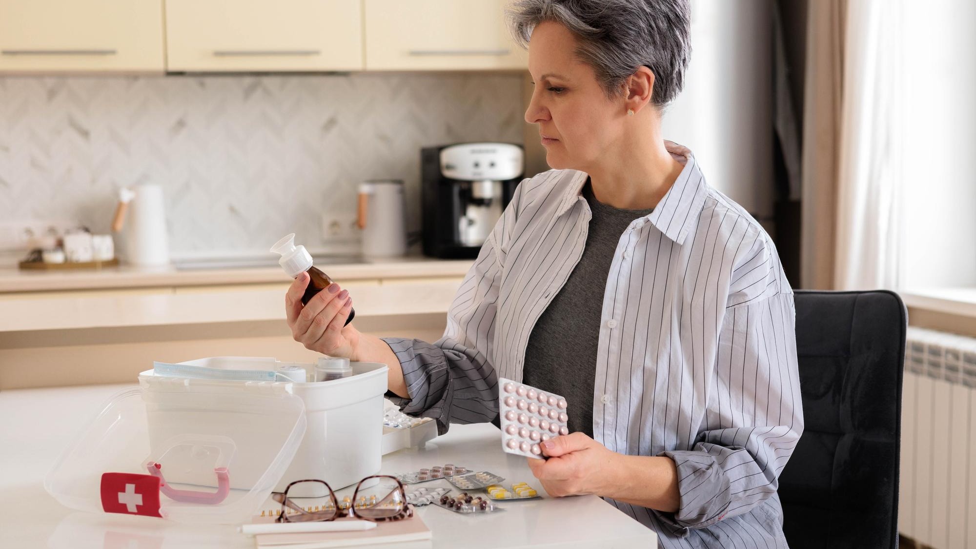 Beautiful aged woman pensioner aged with gray hair checking medicines at domestic first aid kit