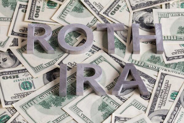 The words ROTH IRA laid with aluminium letters on the US dollar banknotes background with selective focus