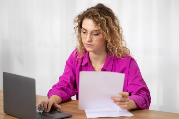 Remote work young woman working with papers and laptop at home office