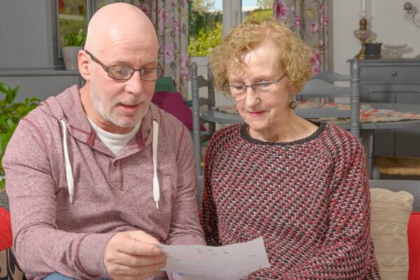 Mature man with woman holding paper on sofa at home
