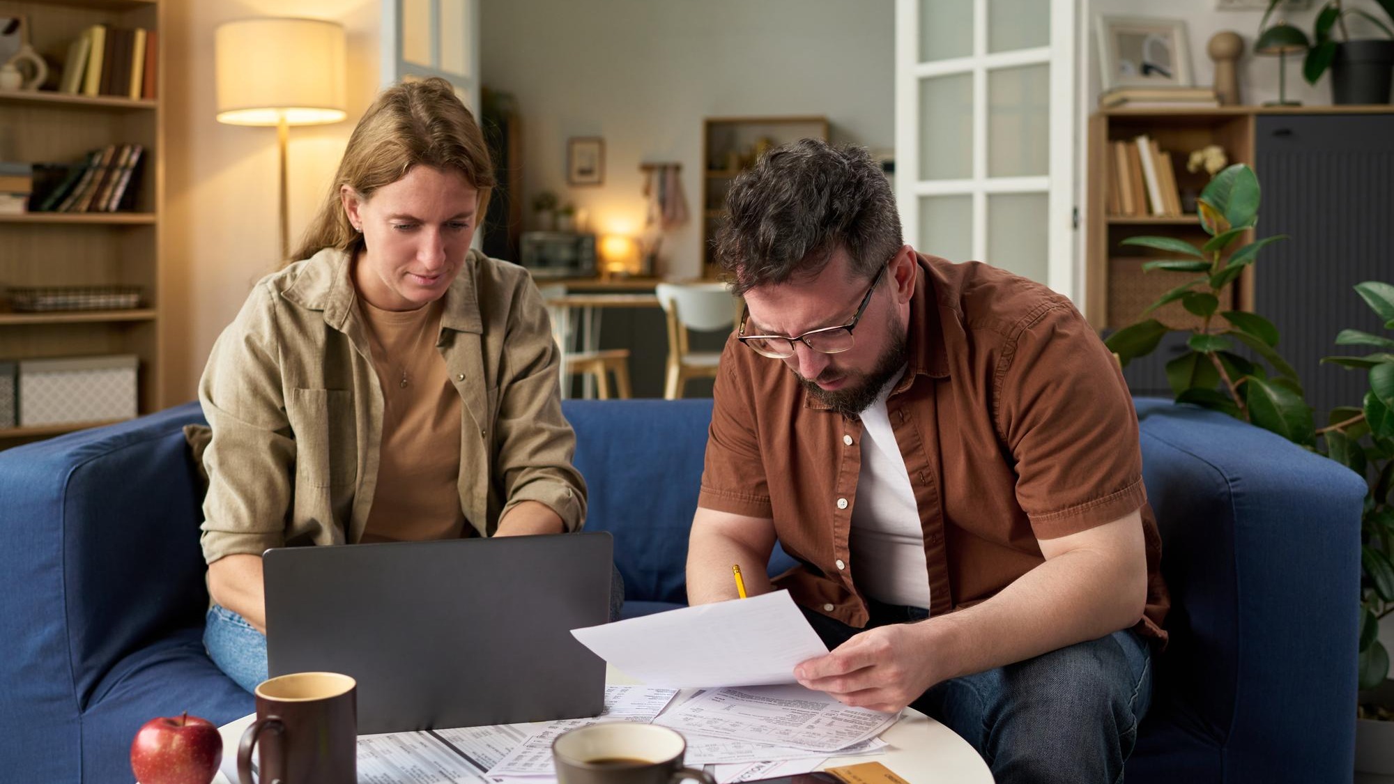 Caucasian young adult man and woman reviewing financial papers while paying taxes