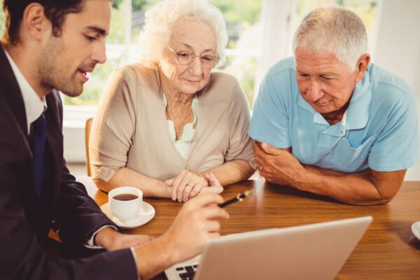 Businessman showing laptop to senior couple at home