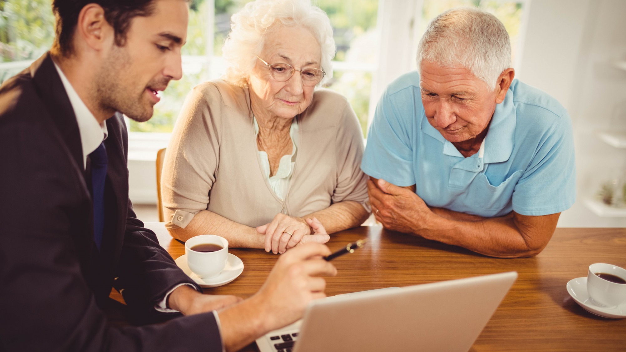 Businessman showing laptop to senior couple at home