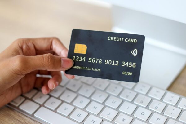 Hand Showing Blank Black Credit Card Mockup Against Keyboard Background