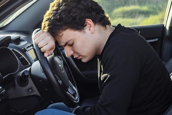 a young man is tired on the road and sleeps on the steering wheel of a car