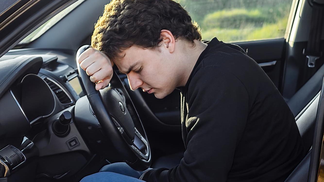 a young man is tired on the road and sleeps on the steering wheel of a car