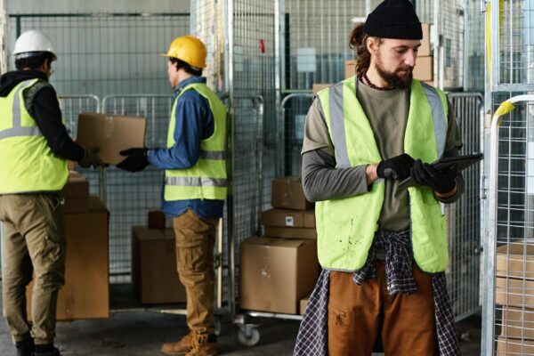 Young engineer in reflective jacket looking at tablet screen while networking
