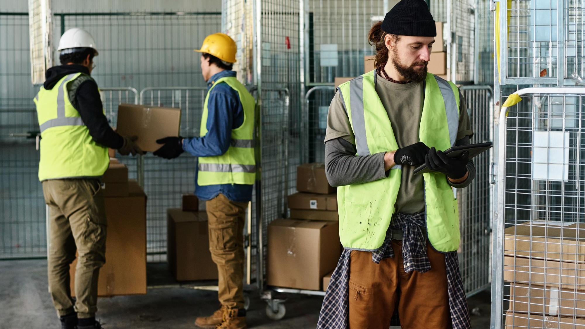 Young engineer in reflective jacket looking at tablet screen while networking