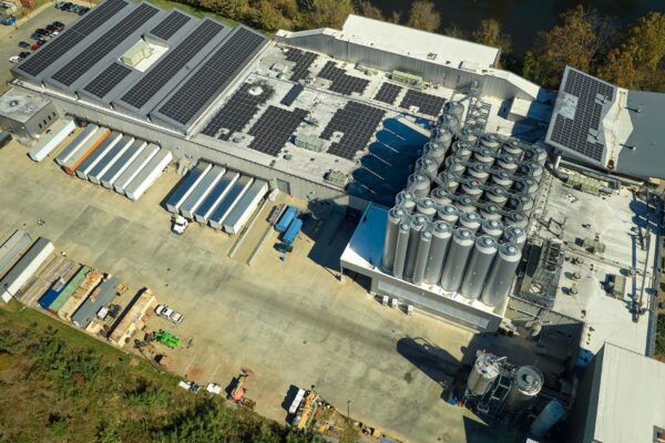 Aerial view of solar power plant with blue photovoltaic panels mounted on industrial building roof for producing green ecological electricity Production of sustainable energy concept
