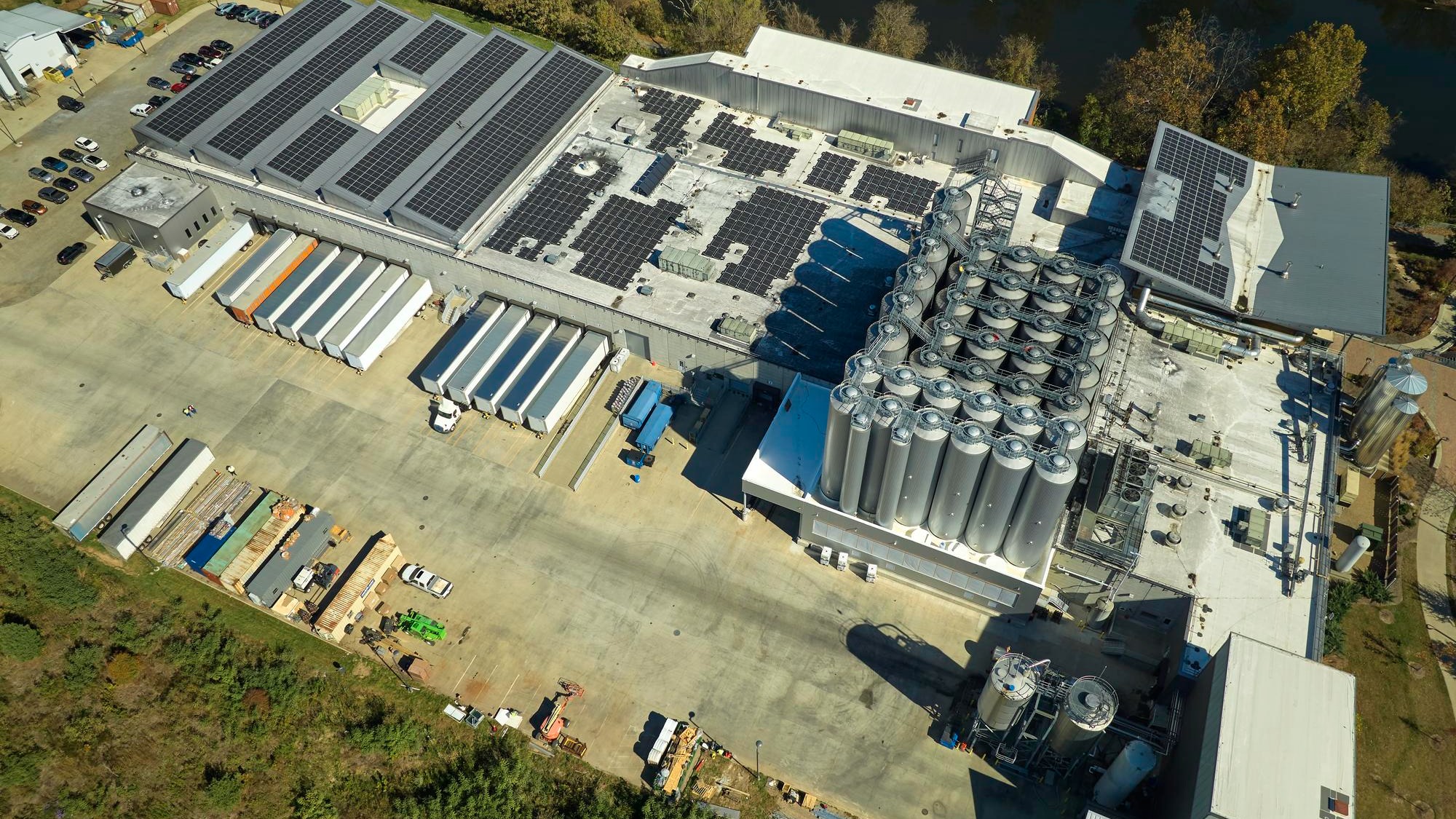Aerial view of solar power plant with blue photovoltaic panels mounted on industrial building roof for producing green ecological electricity Production of sustainable energy concept