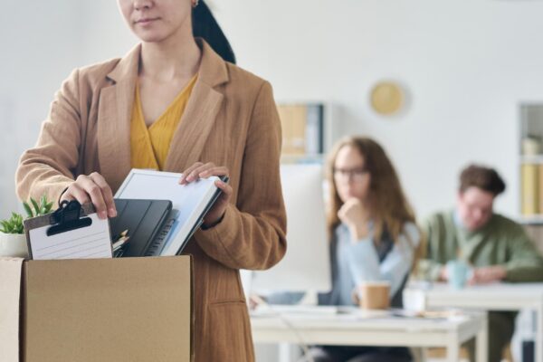 Young businesswoman packing her things in cardboard box in office after her layoff