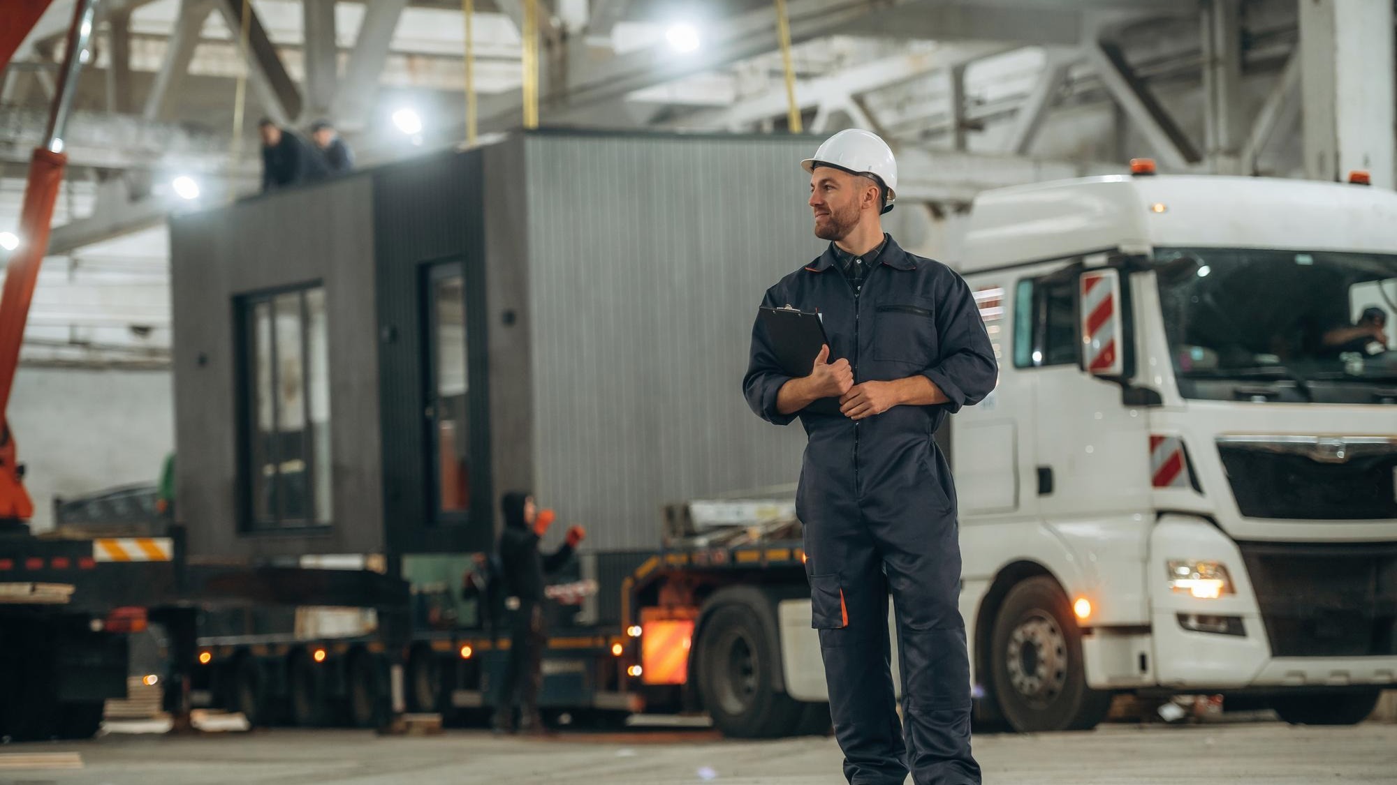 house is transported by a truck Male worker is in the modern warehouse or manufacturing company