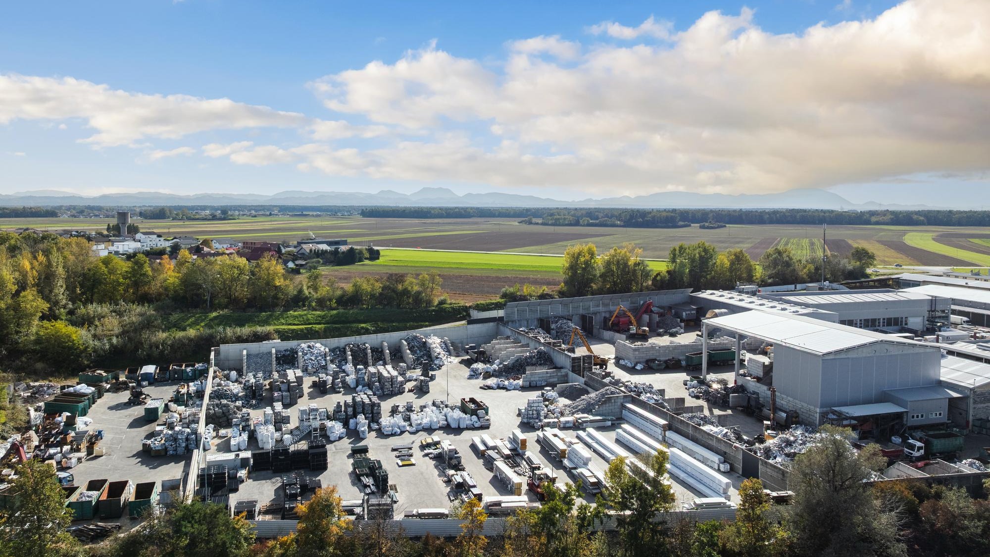Aerial view of a recycling yard showing large scrap metal piles processing areas and heavy machinery