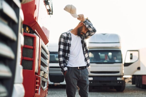 Tired walking outside Young truck driver is with his vehicle at daytime